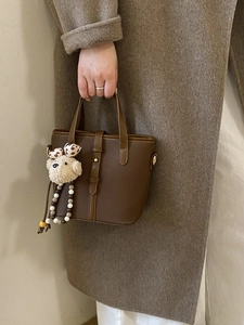 Deep brown pebble leather bucket bag with top handle and cute plush bear charm decoration