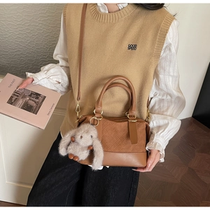 Detail of a brown woven pattern pillow bag with a cute plush bunny charm and top handle