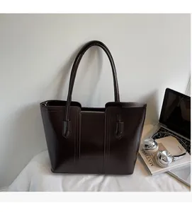 Deep brown faux leather tote bag shown in a professional urban office setting