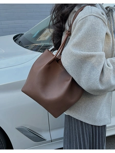 Detail of premium brown pebble leather tote bag shown in a stylish outdoor setting