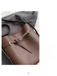 Detailed macro view of dark brown litchi grain leather bucket bag with silver buckle