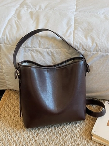 Retro dark brown bucket bag in synthetic leather with white stitching and shoulder strap
