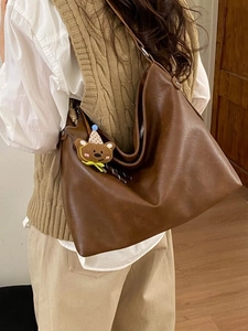 Sac fourre-tout hobo en similicuir marron avec breloque ours, porté par un mannequin