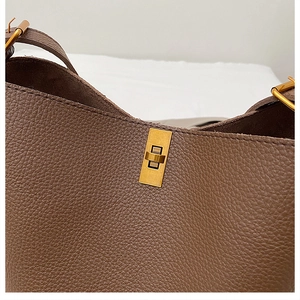 Detail shot of vintage brown pebble leather handbag with gold twist lock and fine stitching