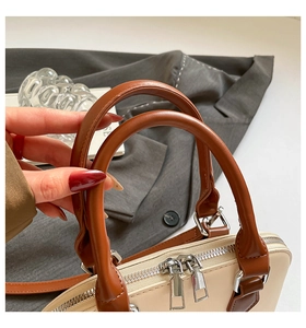 Detail of retro shell bag featuring smooth round handles and silver dual metal zippers