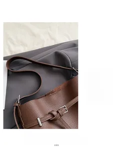 Detail of brown lychee leather bucket bag featuring a wide strap and silver buckle
