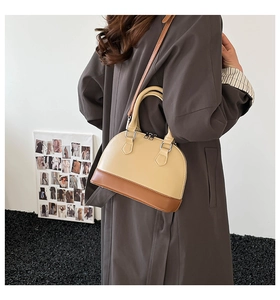 Detail of two-tone shell handbag with premium leather texture and reinforced handle stitching