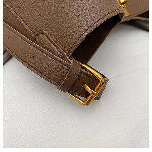Detail of brown litchi pattern leather bag with golden metallic lock and neat stitching