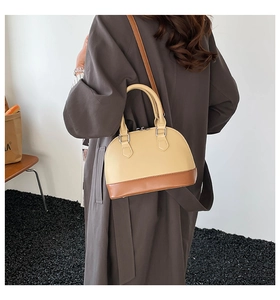 Model wearing a two-tone minimalist shell bag with beige body and dark brown base
