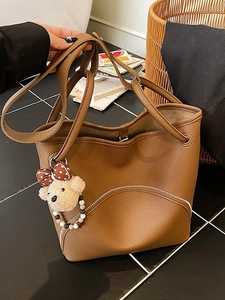 Caramel brown pebbled leather bucket bag with teddy bear charm and metal zipper detail