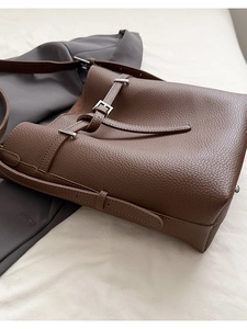 Close-up of caramel brown lychee leather bucket bag with silver buckle and shoulder strap