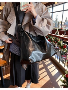 Close-up of a black textured leather hobo bag with adjustable strap in a cafe setting