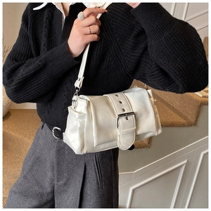 Detailaufnahme einer weißen Lackleder-Schultertasche mit markanter silberner Gürtelschnalle