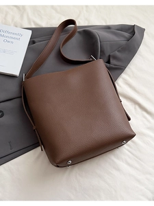 Detail of brown litchi leather bucket bag showing silver metal feet on bottom base