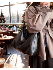 Close-up of black glossy crackle texture tote bag shown in a cozy Christmas cafe setting