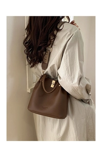 Detailed texture of brown pebble leather bucket bag with decorative ethnic wide strap