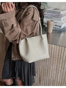 Close-up of minimalist cream tote bag with litchi grain texture and long shoulder straps