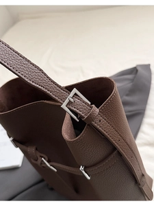 Close-up of deep brown lychee texture leather bucket bag with silver buckle and fine stitching