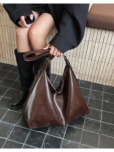 Detail of vintage brown leather hobo bag with oily texture and adjustable strap