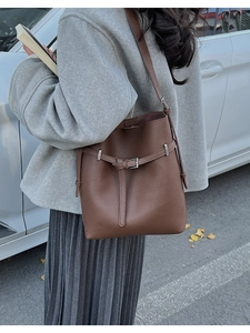 Deep brown litchi pattern leather bucket bag shown in a professional outdoor street style setting