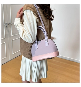 Detailed side view of a light purple leather shell bag with pink base on a model