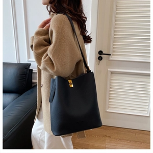 Detail of black lychee grain leather tote bag with a golden twist lock closure and shoulder strap