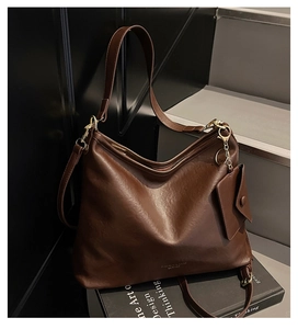 Dettaglio della grande borsa tote marrone scuro con mini portamonete sui libri