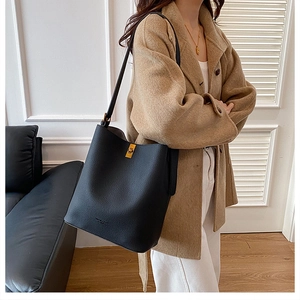 Detail showing high-quality black litchi grain leather bucket bag with gold metal buckle