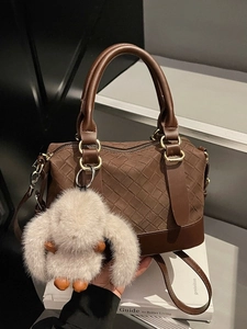 Retro deep brown woven texture pillow bag with a plush charm on a minimal background