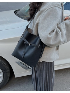 Detail of black pebbled leather bucket bag with silver buckle strap in street style setting