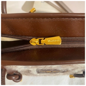 Macro detail of high-quality gold metal zipper and leather patch on faux fur tote bag
