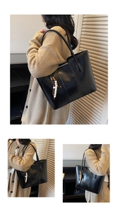Detail of glossy black leather tote bag with unique beaded charm and vertical stitching