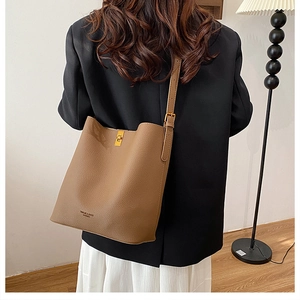 Detail view of the brown pebble leather texture and gold twist lock on the bucket bag