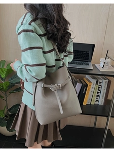 Back view of model wearing a beige lychee pattern bucket bag in a cozy office setting
