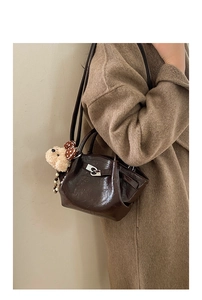 Détail du sac seau en cuir vintage marron avec fermoir argenté et breloque ours en peluche