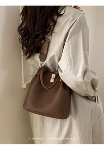 Detail of vintage brown bucket bag with lychee texture and geometric woven strap