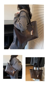 Macro detail of deep brown leather tote bag with elegant vertical stitching and bead charm