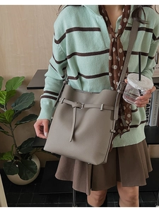 Detailed view of elephant gray leather bucket bag worn by model in minimalist setting