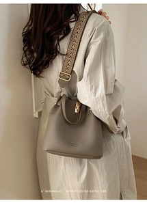 Detail of taupe lychee leather bucket bag with a colorful woven geometric shoulder strap