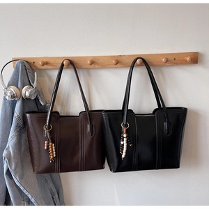 Detail view of large PU leather tote bags in black and coffee brown with beaded charms