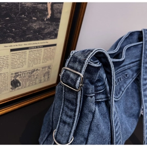 Close-up of blue washed denim bag with embossed UTING text and silver metal buckle