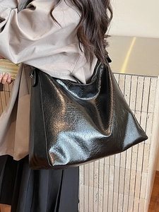 Glossy black large capacity tote bag with pleated texture shown on model in studio