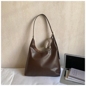 Detail view of dark brown leather tote bag with striped lining and cute bear charm