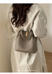 Detail of taupe pebbled leather bucket bag with gold twist-lock and brand logo