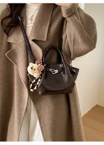 Détail d'un sac à main vintage en cuir ciré marron avec fermoir argenté et breloque