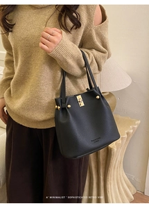 Detail of black lychee texture leather bucket bag with gold metal clasp and logo