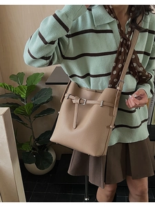 Close-up of a brown bucket bag with lychee grain texture and adjustable shoulder strap