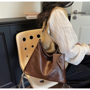Detailed view of deep brown leather tote bag with gold logo and mini detachable pouch