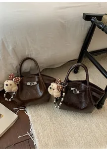 Détail de sacs seaux marron brillant avec fermoirs argentés et charms ours en peluche