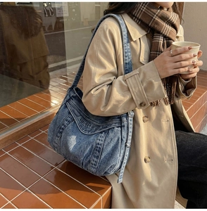 Detail of blue denim tote bag featuring pleated texture and letter embroidery accents